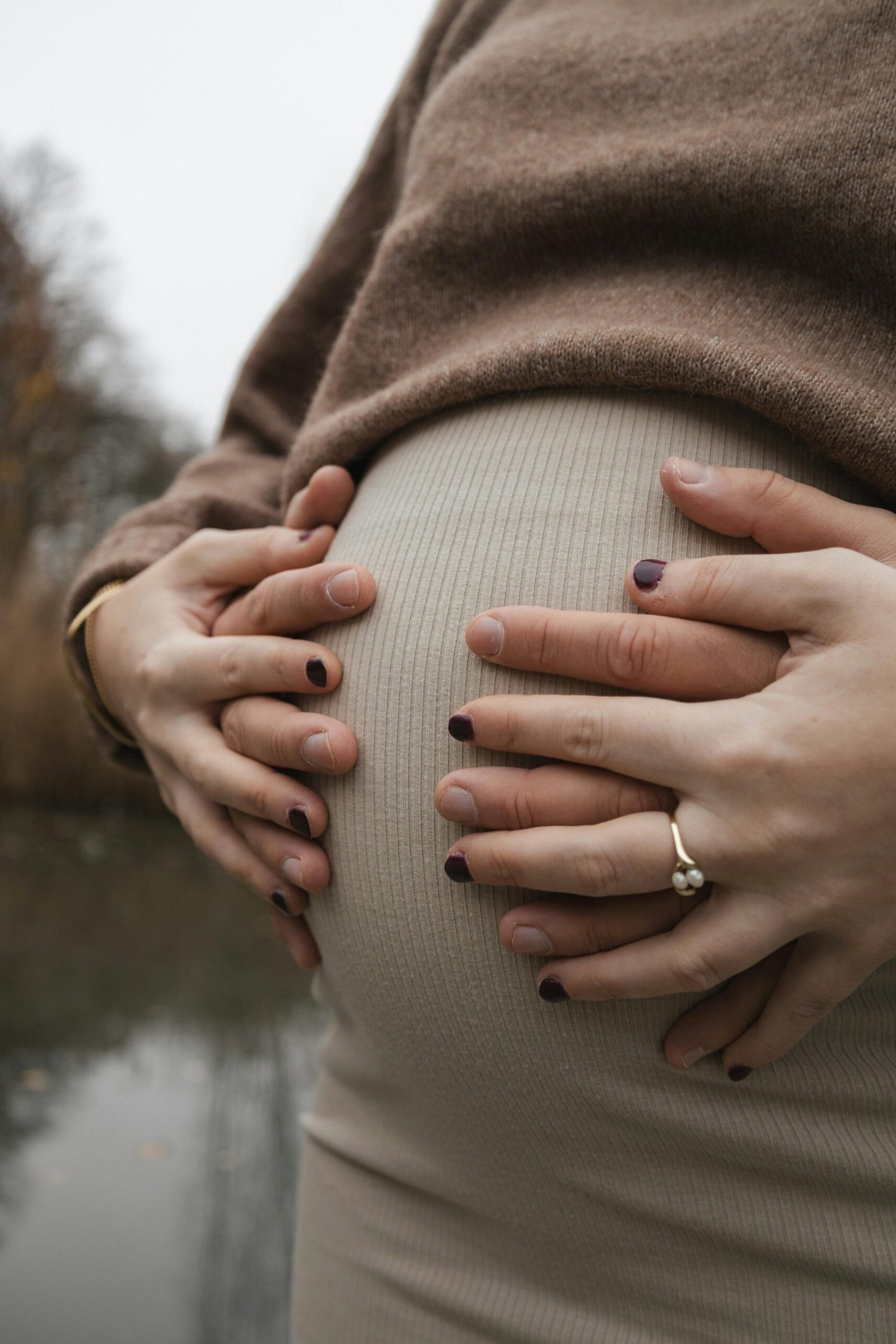 Mehrere Hände liegen behutsam auf einem Babybauch